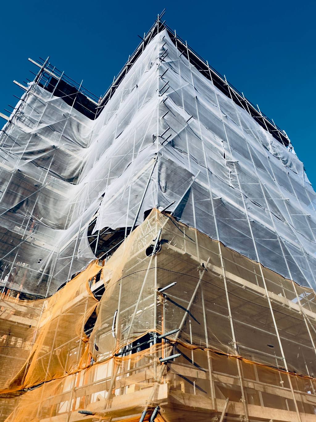 Building under construction wrapped in scaffolding and netting